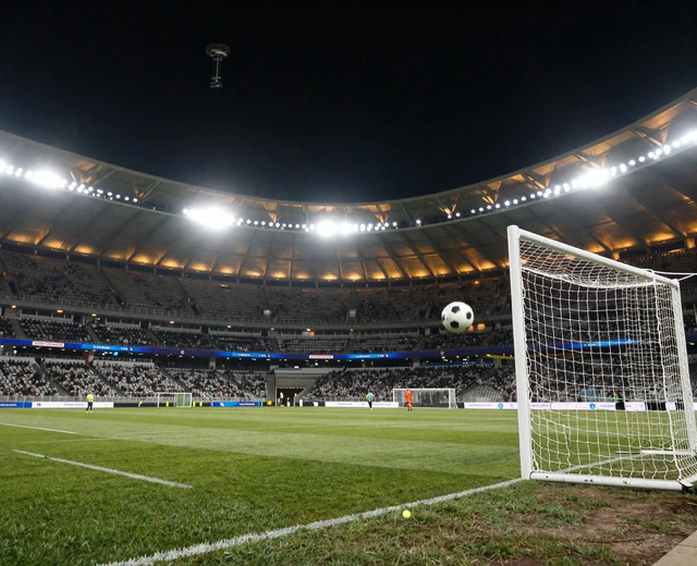 Flutlicht-Fu&szlig;ballstadion bei Nacht mit Ball im Flug Richtung Tor als Symbol f&uuml;r Golazzo Sportwetten